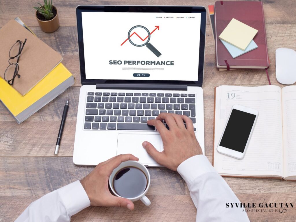 Laptop showing SEO performance graph with magnifying glass icon, coffee cup and workspace items.