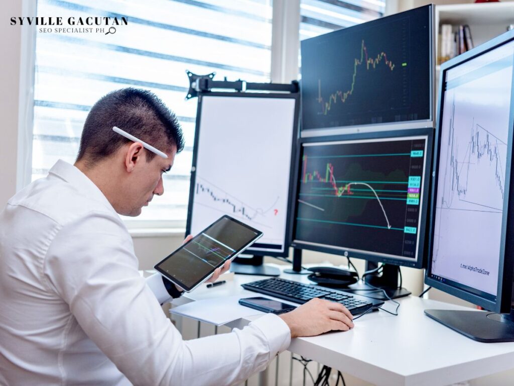 Professional analyzing financial charts on multiple monitors in white office setup.