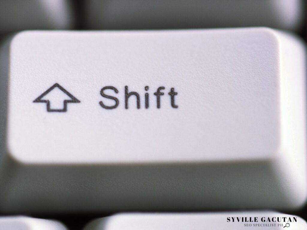 Close-up macro shot of white keyboard Shift key with arrow symbol.