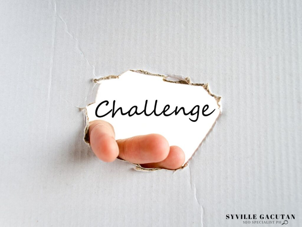 Hand revealing the word "Challenge" through torn white paper.
