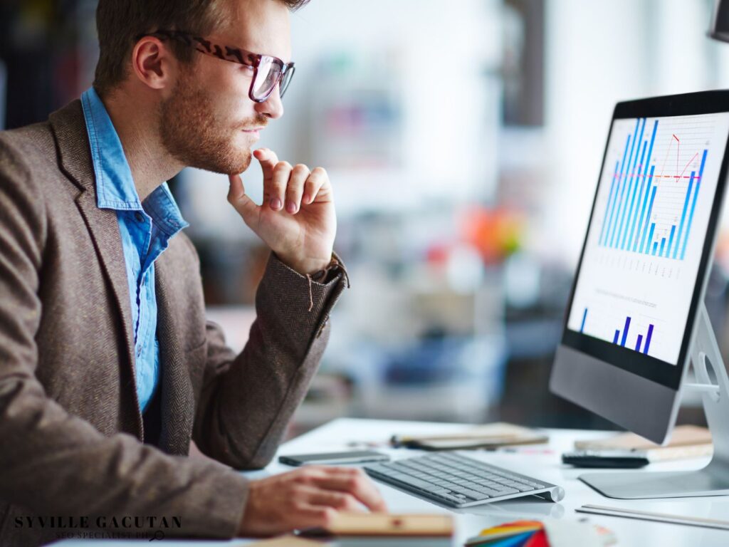 Professional analyzing data charts on computer monitor in office setting.