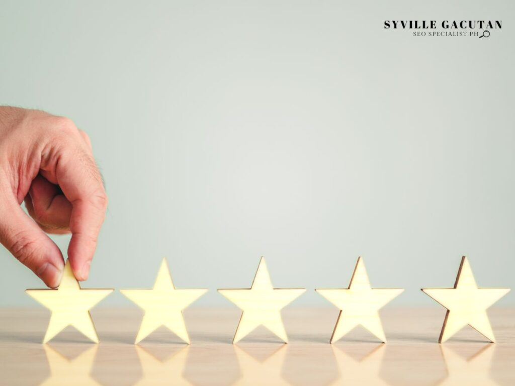 Hand placing wooden star in a row of five stars on light surface.