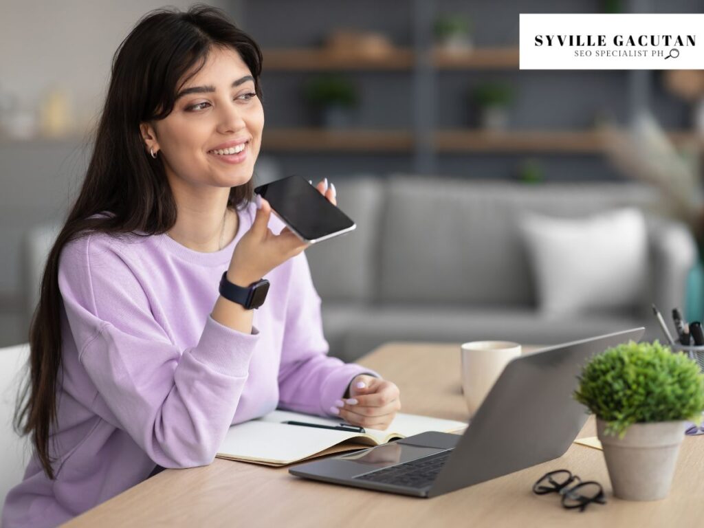 Woman using voice search on her phone while working at a desk.