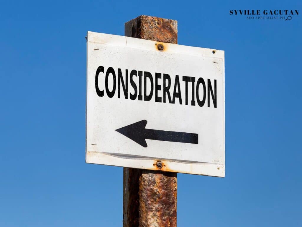 White directional sign with "CONSIDERATION" text and left-pointing arrow against blue sky.