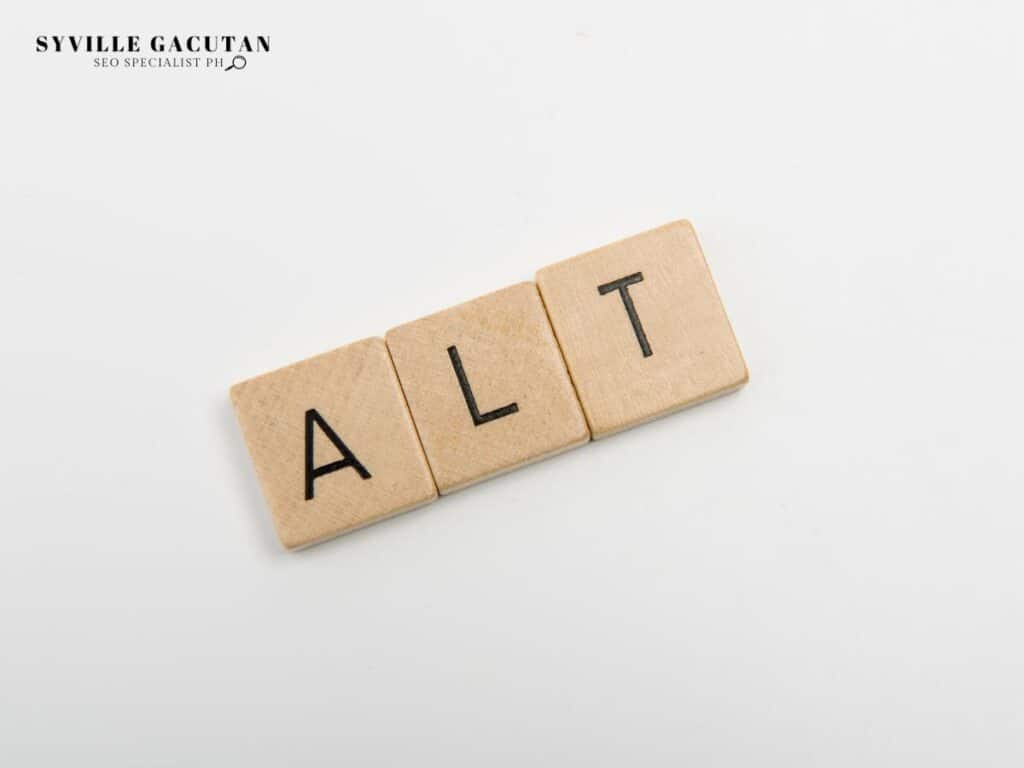 Wooden Scrabble tiles spelling out "ALT" on a white background.