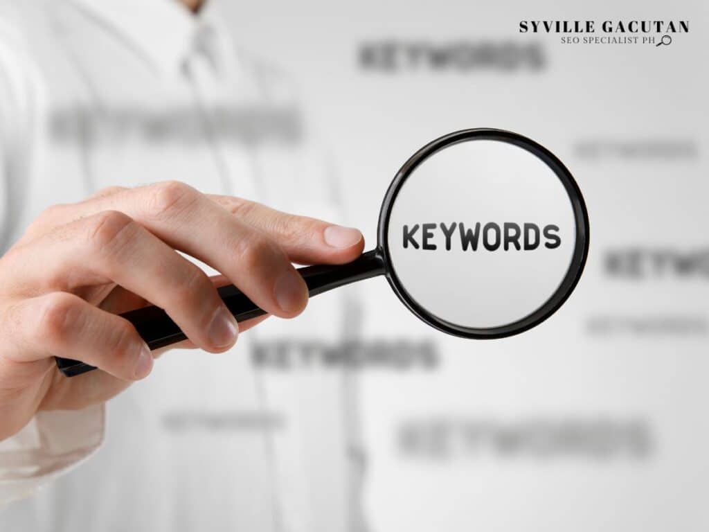 A magnifying glass highlighting the word "KEYWORDS" on a blurred background.