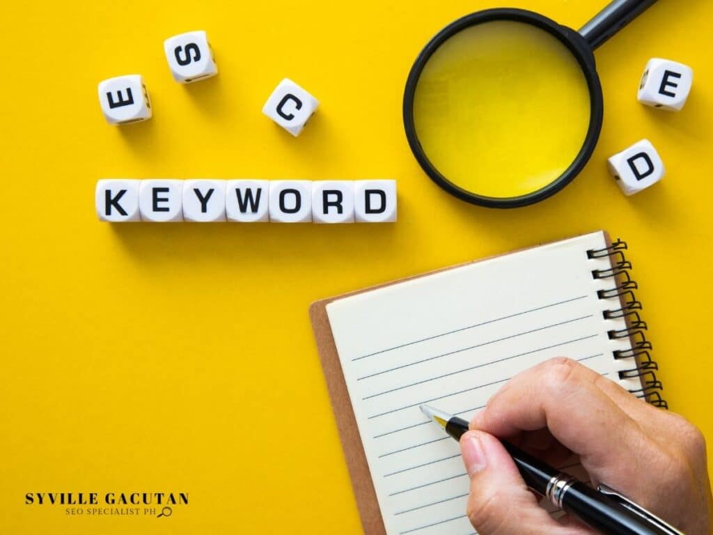 White letter cubes spelling "KEYWORD" with magnifying glass and notepad on yellow background.