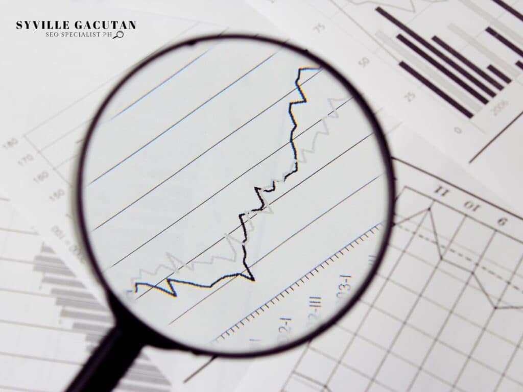 Magnifying glass focusing on a rising line graph over data sheets.