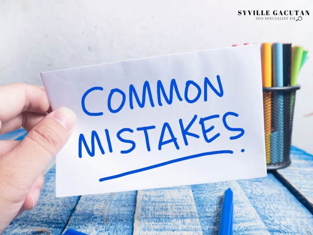 Hand holding white card with "Common Mistakes" in blue text on wooden desk.