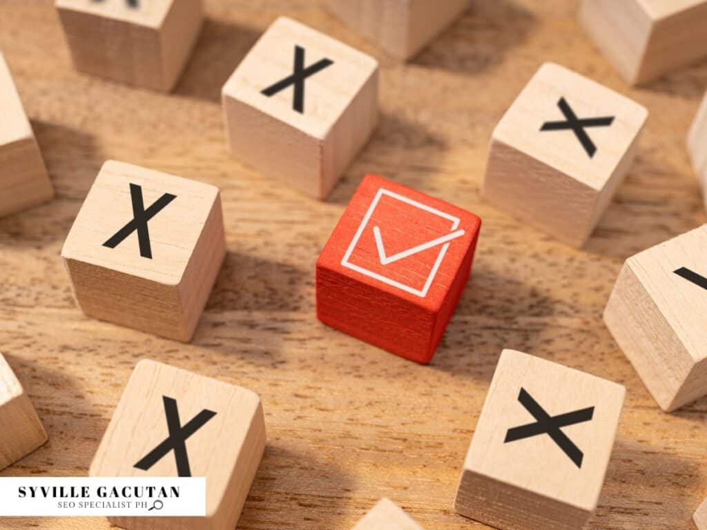 Wooden blocks with "X" letters surrounding one red block with checkmark symbol on wooden surface.