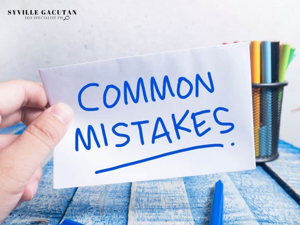Hand holding card with "COMMON MISTAKES" written in blue, pen and pencil holder in background.