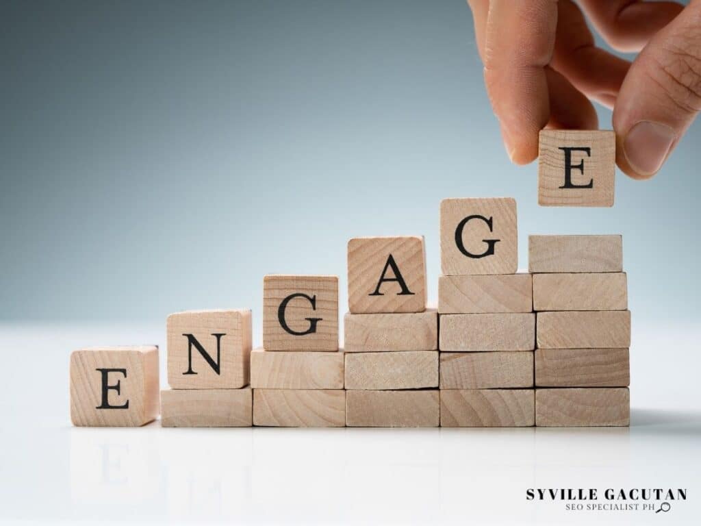 Wooden blocks spelling "ENGAGE" arranged in ascending steps with hand placing final letter.