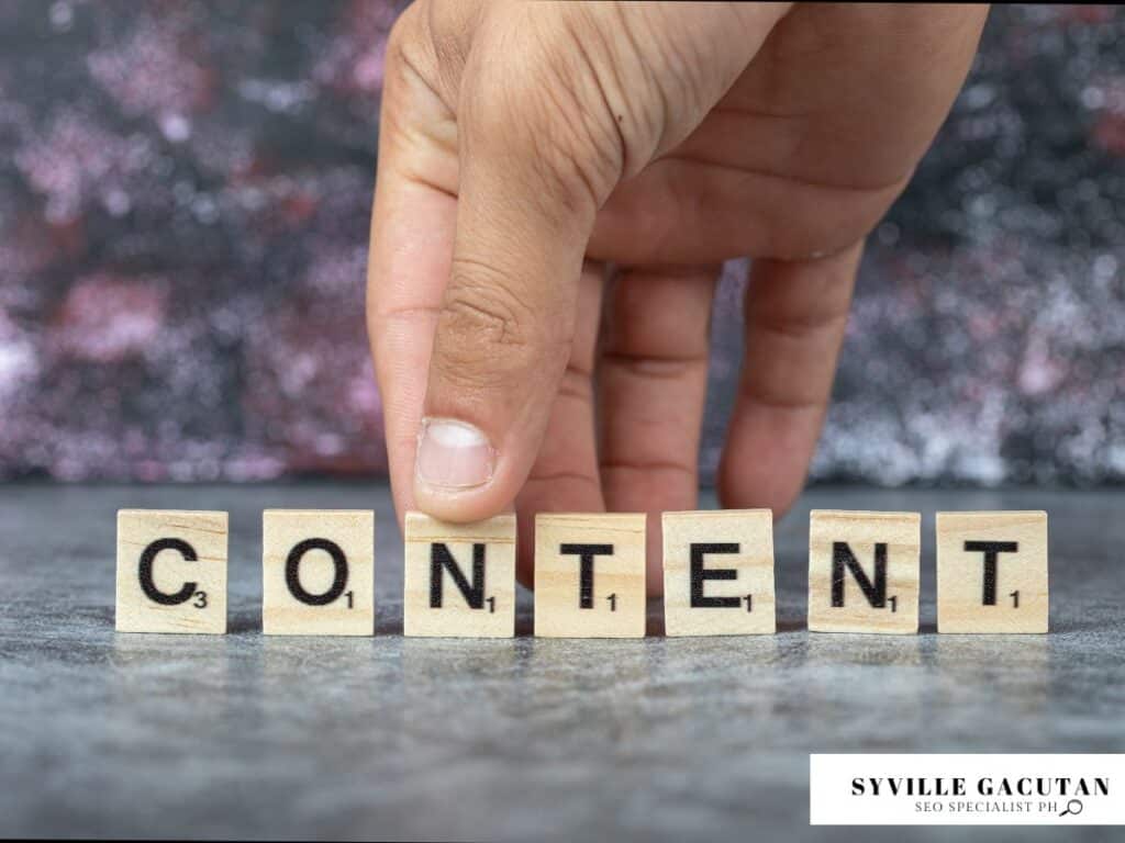 Hand arranging wooden letter tiles spelling out "CONTENT" on textured gray surface.