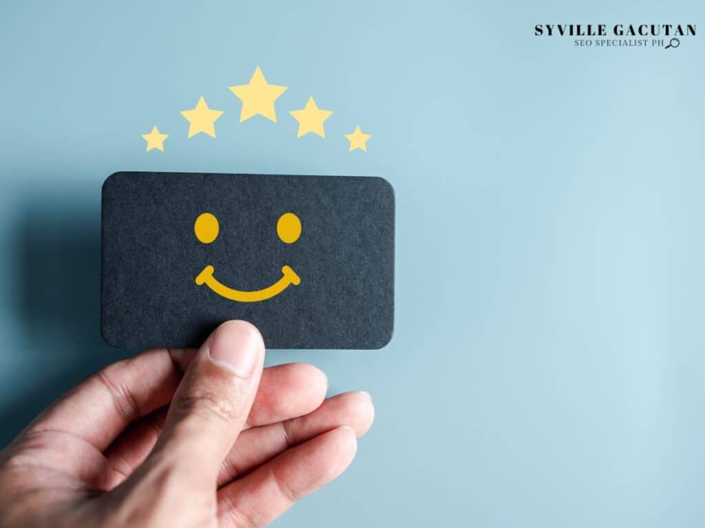 A hand holding a card with a yellow smiley face and stars above it.