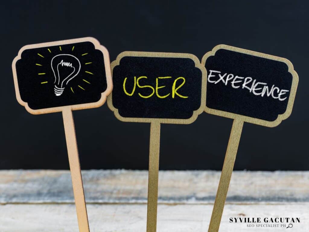 Three small chalkboard signs showing lightbulb icon, "USER" and "EXPERIENCE" text.
