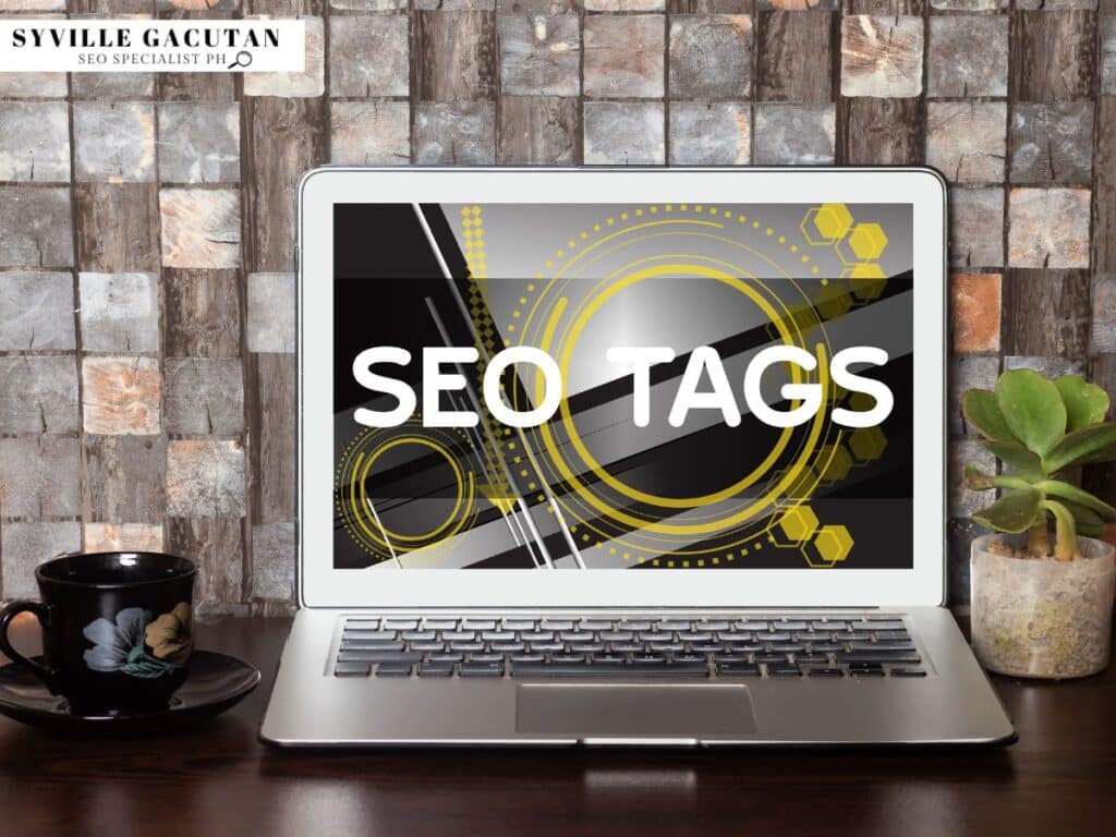 Laptop showing "SEO TAGS" text with geometric yellow designs on screen, coffee cup and plant nearby.