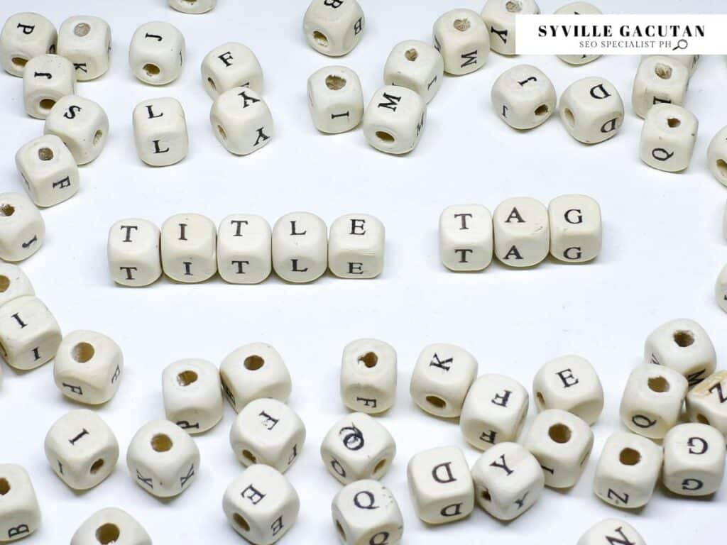 White letter cubes spelling "TITLE" and "TAG" arranged on white surface.