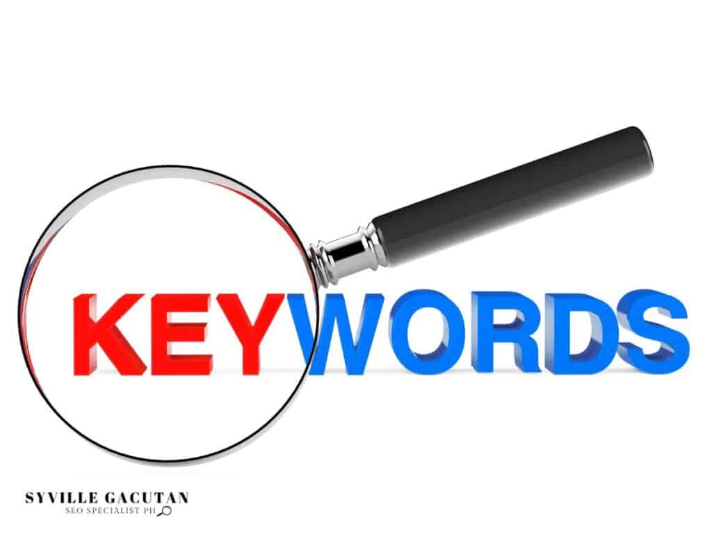 Magnifying glass examining "KEYWORDS" text in red and blue colors with black handle.