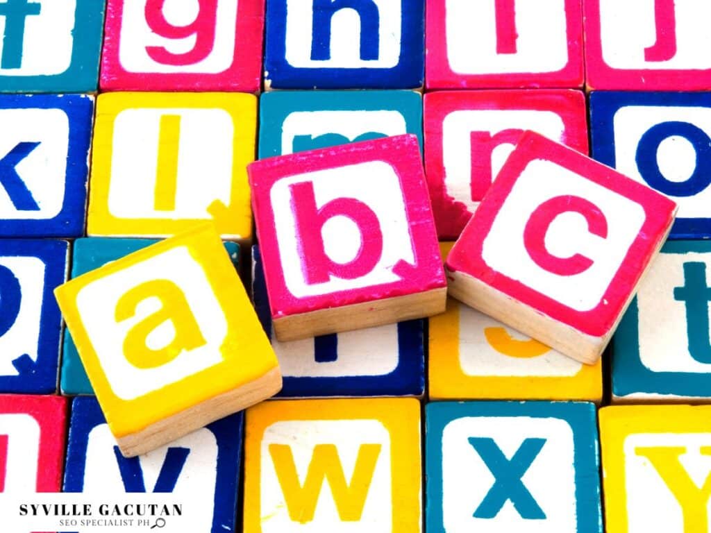 Colorful wooden alphabet blocks with letters "a", "b", "c" arranged on patterned block background.