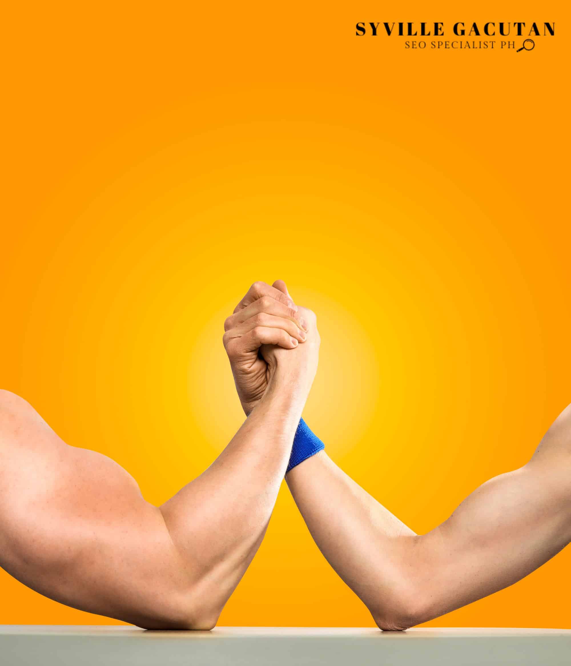 Two muscular arms arm wrestling on a table against a vibrant orange background.