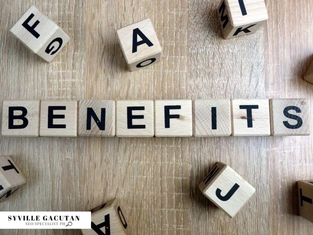 Wooden letter tiles spelling "BENEFITS" on light wooden surface with scattered alphabet blocks.