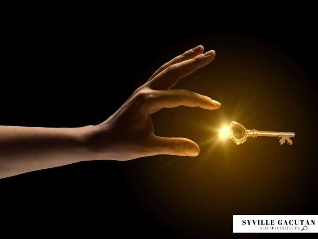 A hand reaching for a glowing golden key against a dark background.