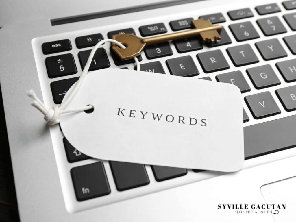 White "Keywords" tag resting on laptop keyboard with gold key.