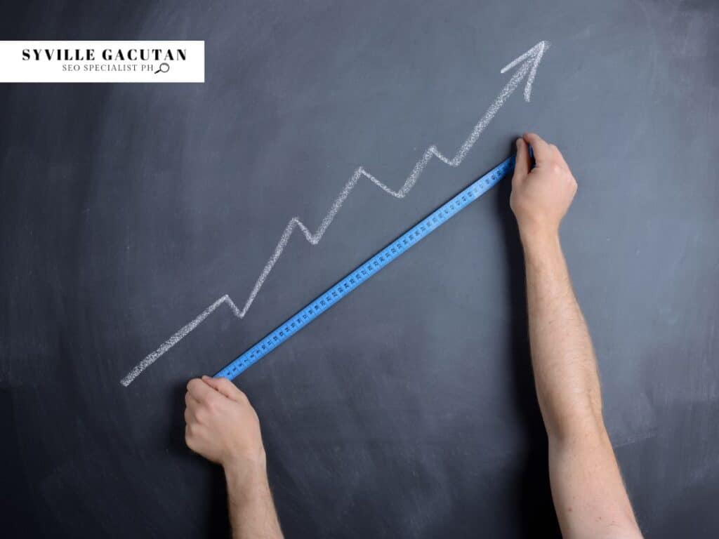 Hands holding blue measuring tape against blackboard with upward trending chalk graph.