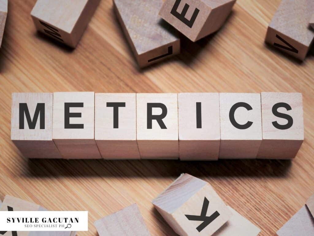 Wooden blocks spelling "METRICS" on a wooden surface.