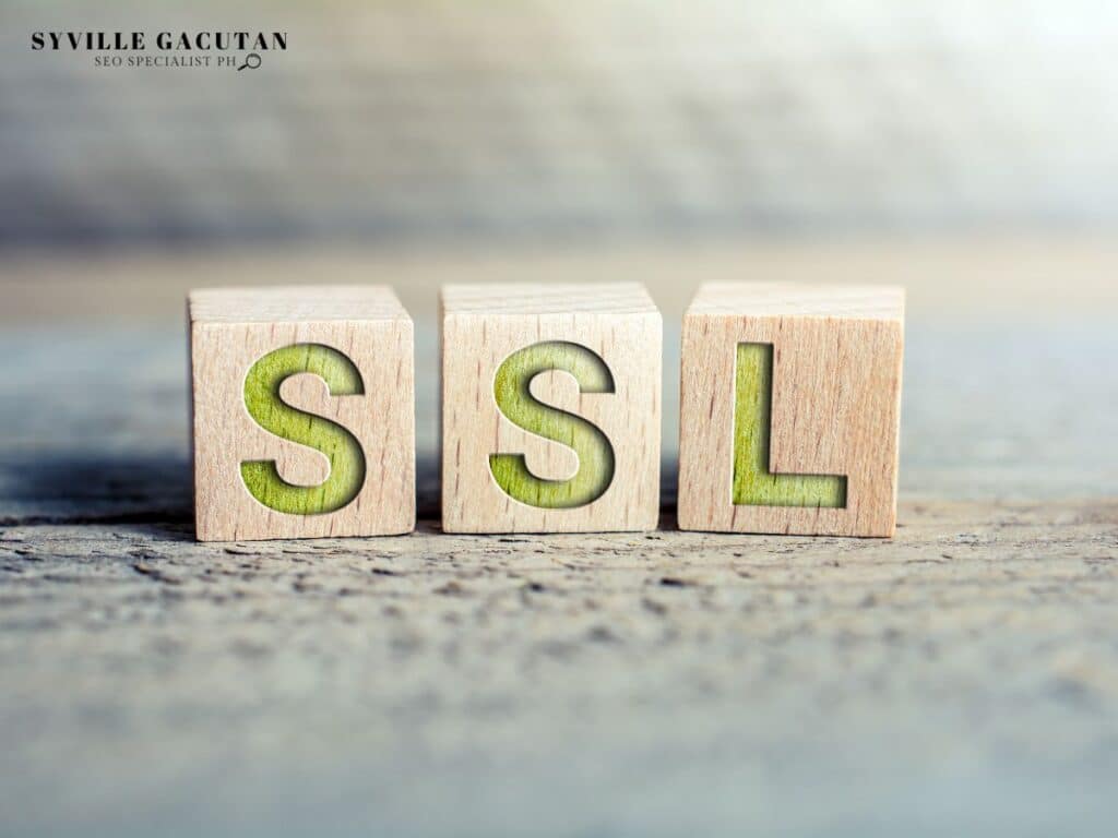 Wooden blocks with green inset letters spelling "SSL" on textured gray surface.