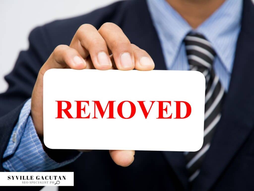Business person holding white card with bold red "REMOVED" text against light background.