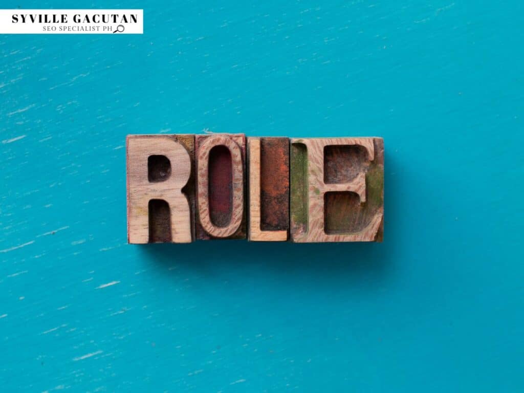 Wooden blocks spelling 'Role' on a teal surface.