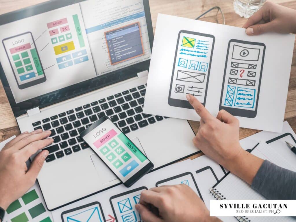 Designers discussing mobile UI layouts with mockup sketches and laptops.