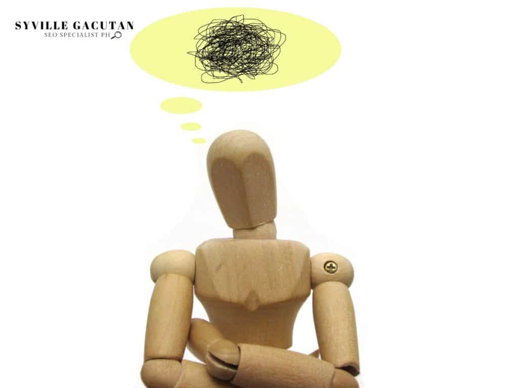 Wooden mannequin with scribbled thought bubble.