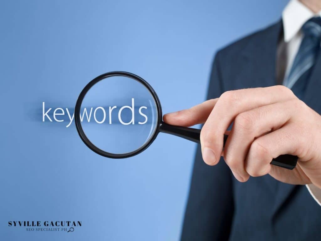 Magnifying glass examining the word "keywords" on blue background, held by suited person.