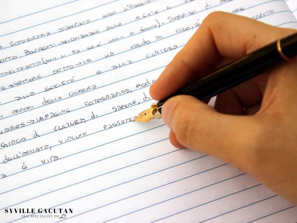 A hand writing in a notebook with a gold fountain pen.