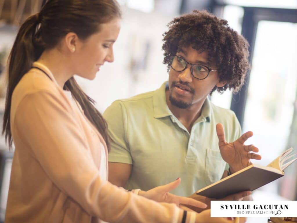 Two people discussing while looking at an open notebook.

