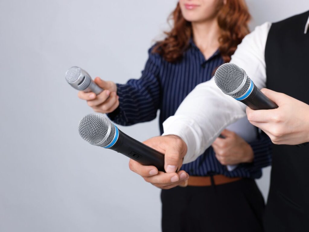 Reporters holding microphones toward a speaker.