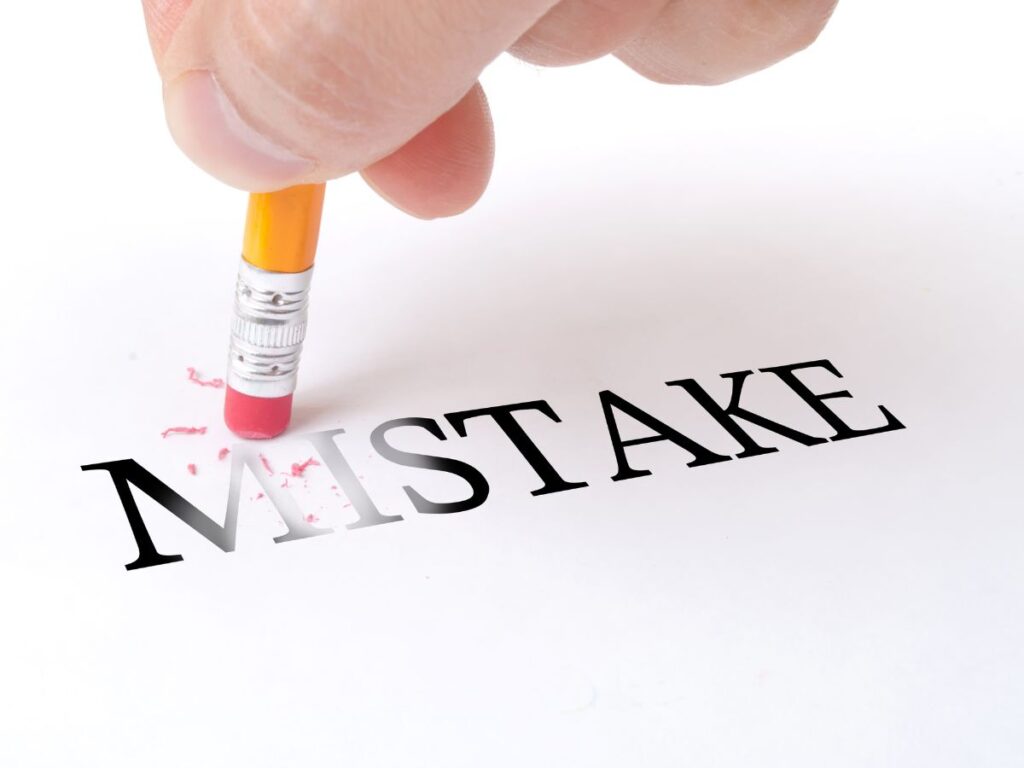 Pencil erasing the letter “I” from the word “MISTAKE.”
