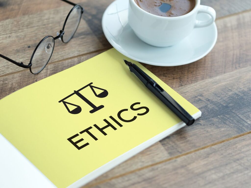 Notebook labeled “ETHICS” beside glasses, pen, and coffee cup.