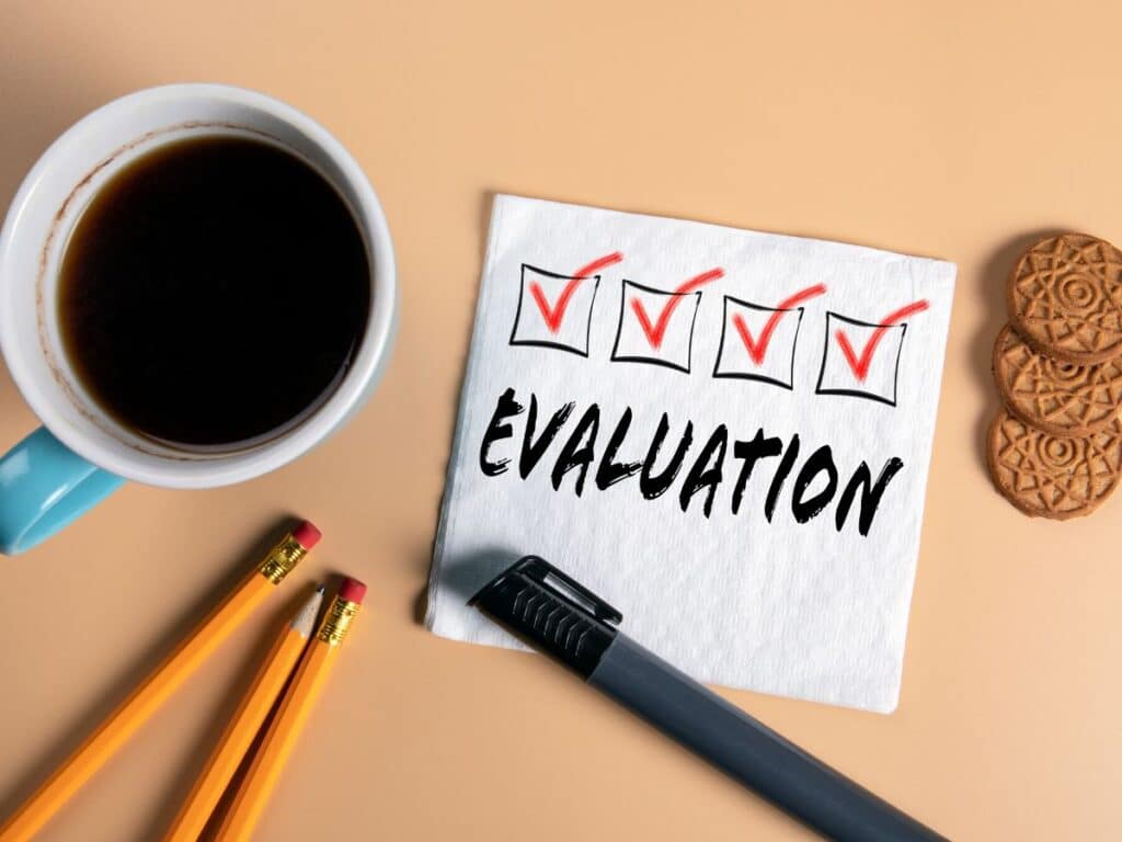 Napkin with “Evaluation” and checkmarks beside coffee and pencils.