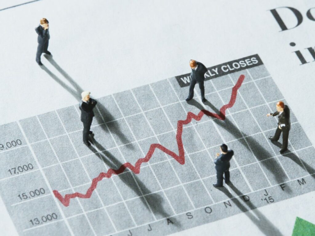 Mini figures standing on an upward trend chart.