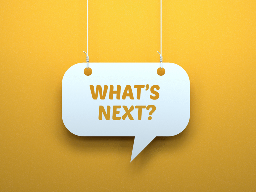 Hanging speech bubble sign reading “What’s Next?” on yellow background.
