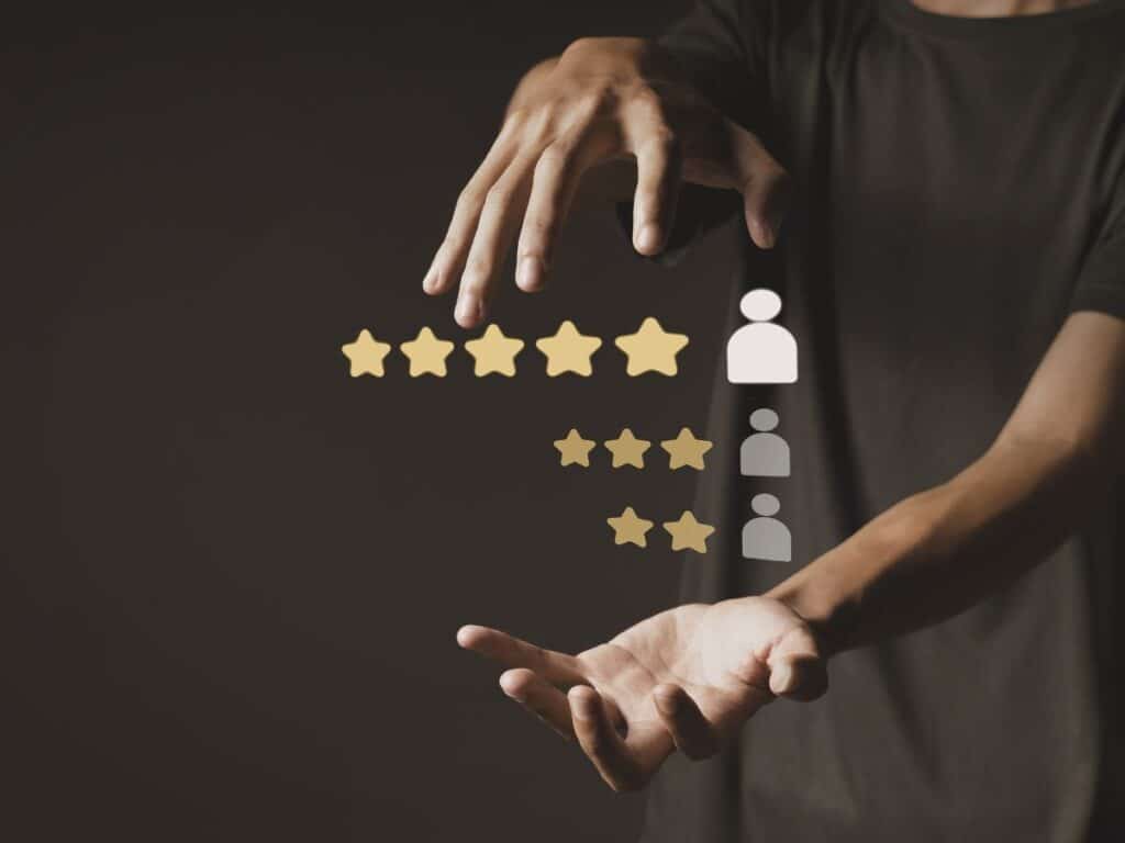 Hands arranging star ratings above customer icons on a dark background.