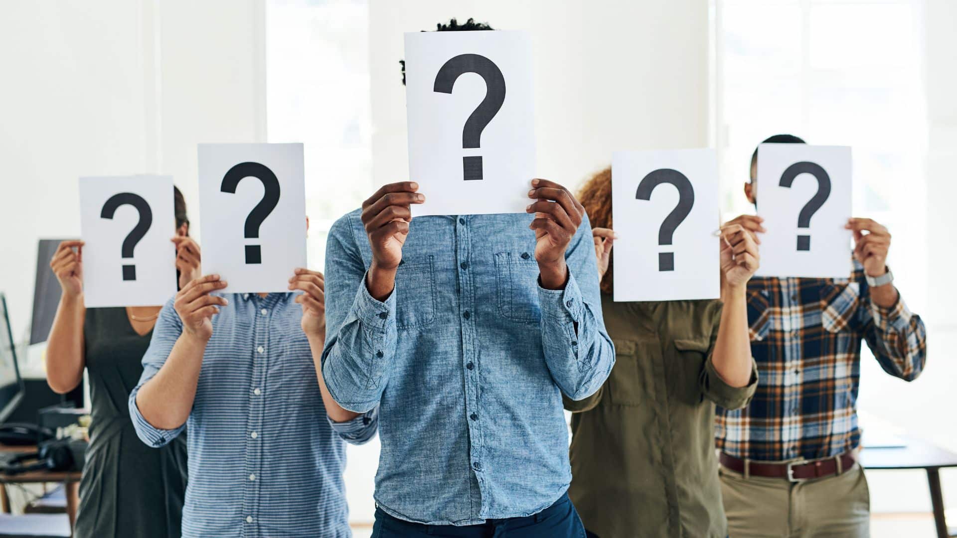 Group holding question mark signs, symbolizing uncertainty or selection.