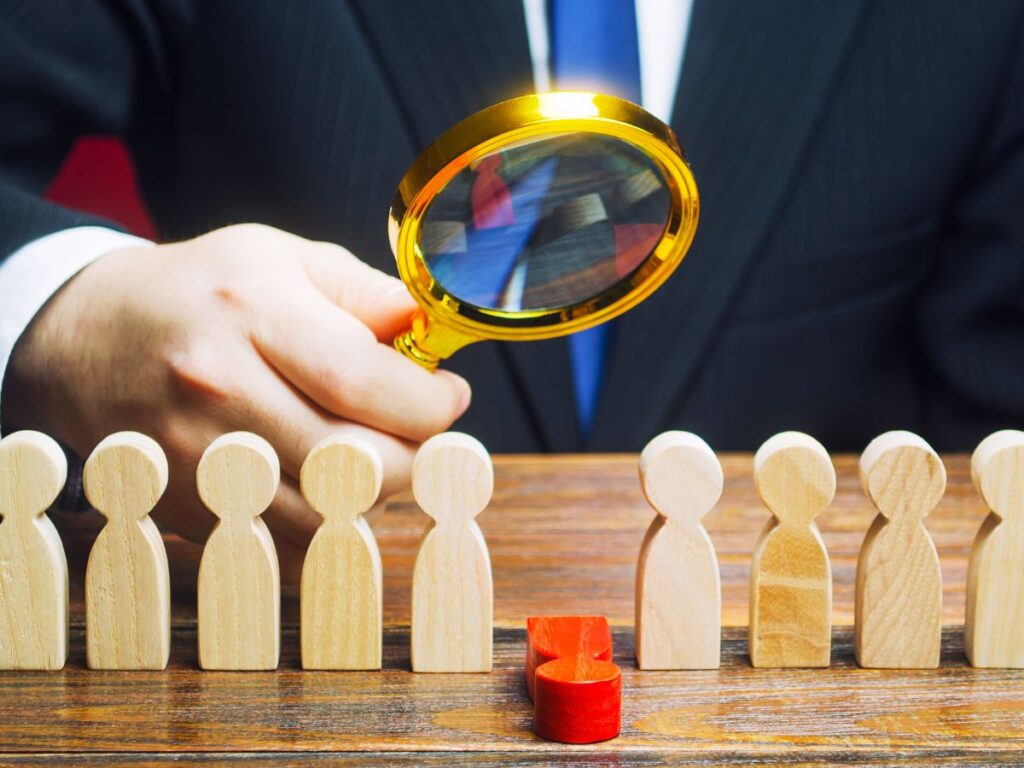 Magnifying glass inspecting wooden figures.