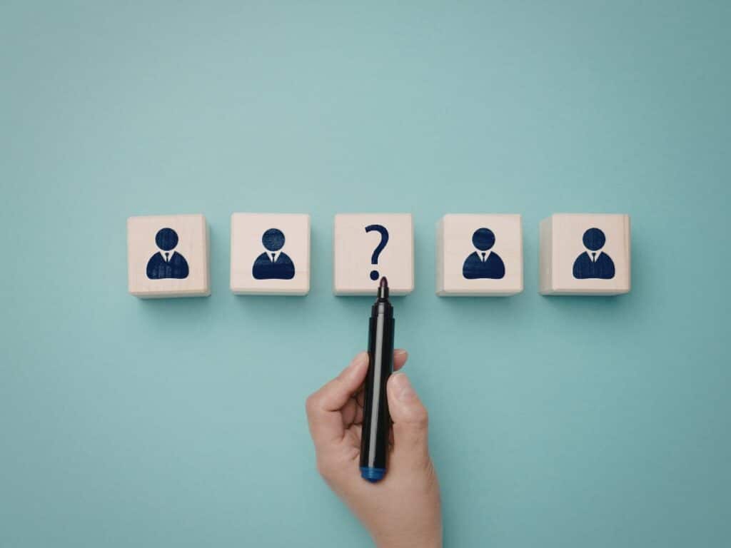 Hand marking question on candidate icons, indicating selection.