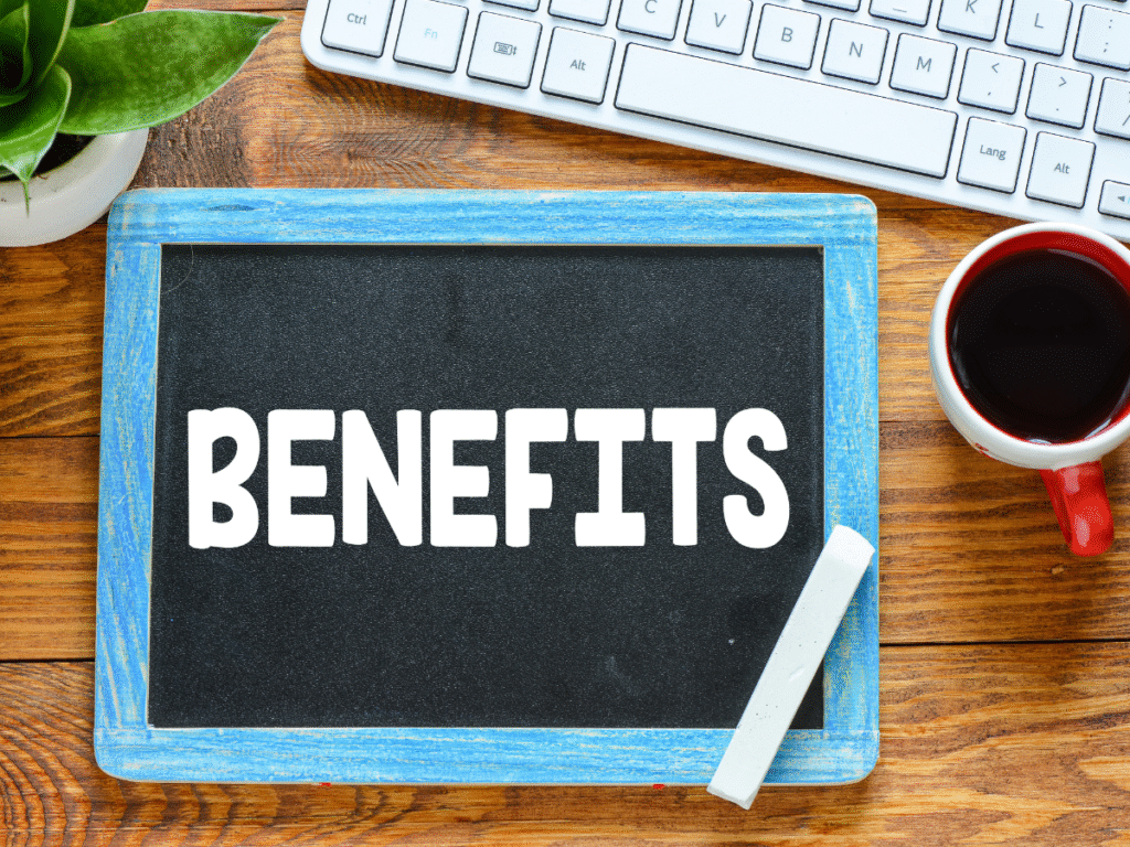Chalkboard labeled “BENEFITS” beside a keyboard, plant, and coffee cup.
