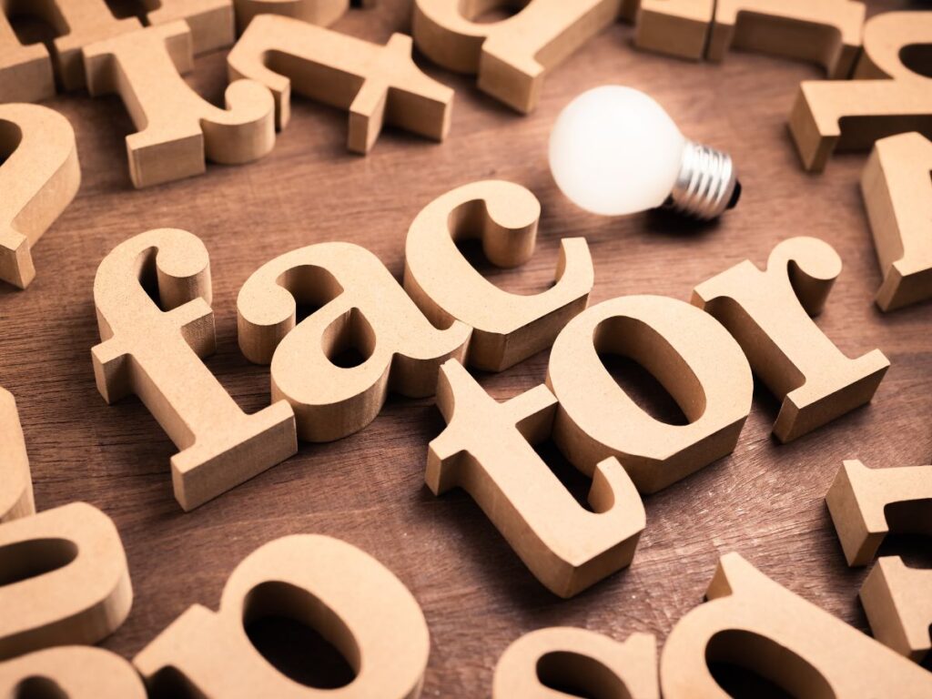 Wooden letters spelling “factor” beside a bulb.