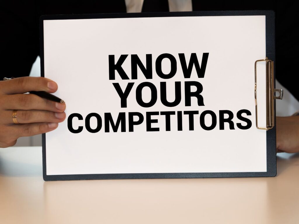 Clipboard sign reading “Know Your Competitors.”